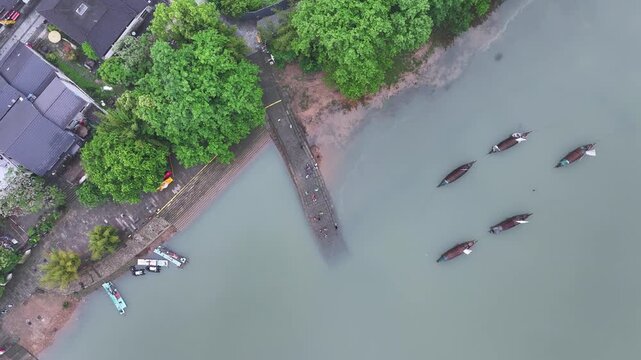 Aerial view of wooden boats moored along the riverside in a Jiangnan water town with traditional architecture