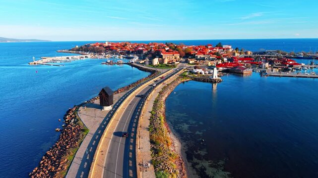 Causeway bridge connecting mainland to a historic town with red roofs in the sea. Aerial view of a narrow road leading to old town Nessebar in Bulgaria.