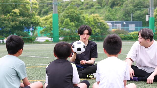サッカーボールを使って指導する少年サッカーチームのコーチ