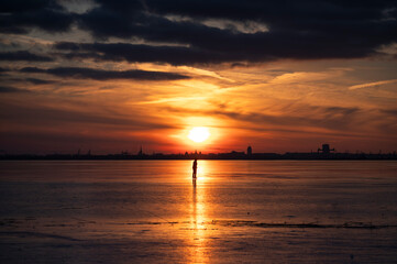 Fototapeta premium A person ice skating on a frozen lake at sunset.