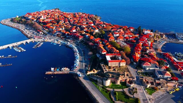 Top view of a dense ancient town on a peninsula with red tiled roofs and old ruins. Aerial view of historic coastal peninsula town Nessebar.