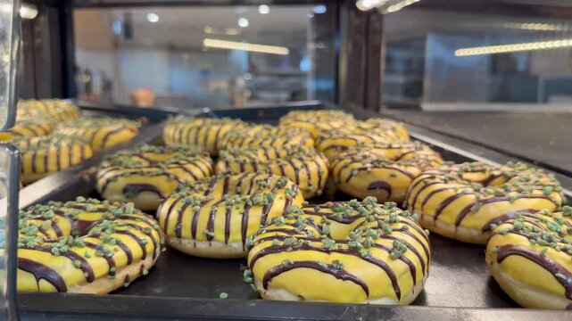 Colorful pistachio donuts and Dubai chocolate donuts arranged on tray with bright glaze, crunchy topping and smooth texture. Colorful pistachio donuts and Dubai chocolate donuts arranged on tray.