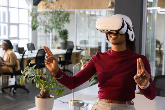 Coworker in VR headset raising hands, initiating virtual UI, data charts appearing for tech demo