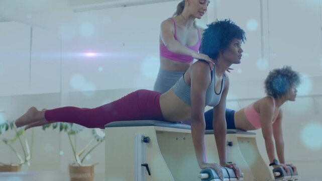 Instructor placing hands on participant's upper back, guiding Pilates chair alignment for fitness