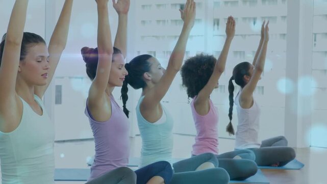 Five women inhaling and raising arms on yoga mats by tall windows, bokeh overlays guiding alignment