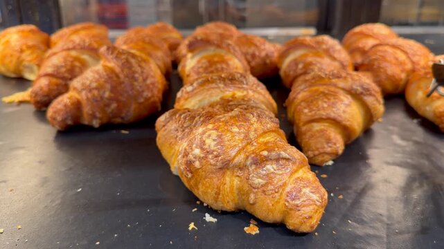 Fresh butter croissants with crispy golden layers displayed on counter in traditional artisan bakery presentation. Warm pastry footage ideal for coffee shop advertising, brunch menu promotion, bakery