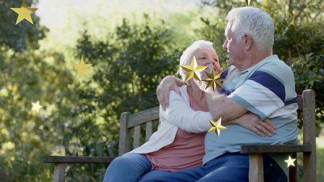 Senior couple on bench man stroking cheek while gold stars drifting from frame two promoting health