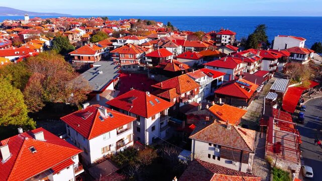 Aerial view of traditional stone and wooden buildings with bright red roofs in a dense neighborhood. Dense urban landscape of historical town houses Nessebar, Bulgaria.