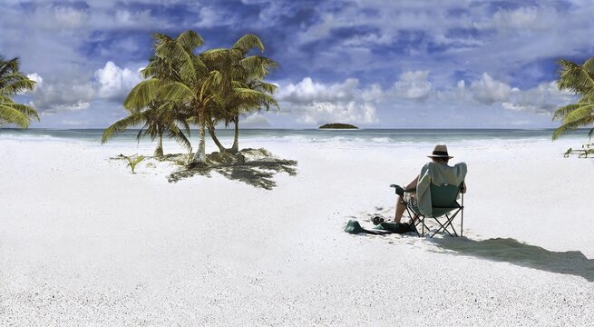 Man wearing sun hat sitting on a chair on a beach in the Caribbean at Punta Allen, Mexico, North America