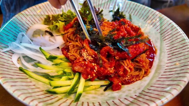 Makguksu stir with chopsticks, a traditional and popular noodle dish enjoyed especially in summer in Korea