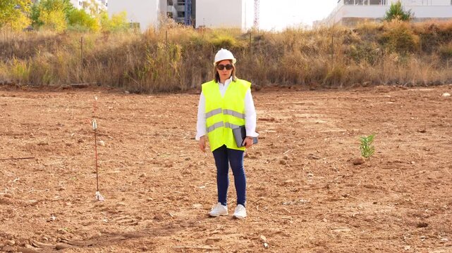 Woman architect wearing a hard hat and safety vest, supervising a building project