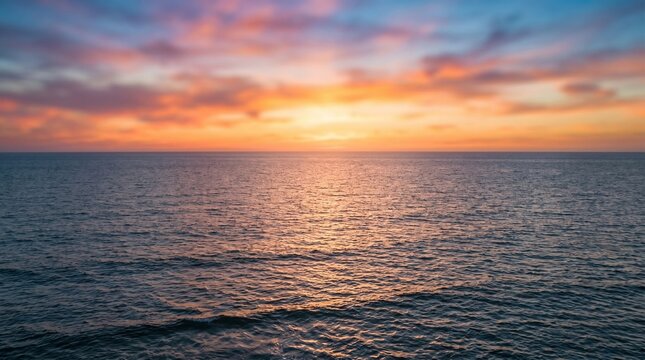 Beautiful sunset over the calm ocean horizon with vibrant orange and blue sky
