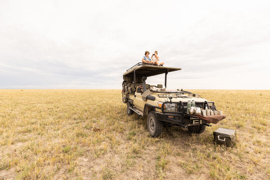 siblings on roof of safari vehicle, Makgadikgadi Park, Botswana, Africa