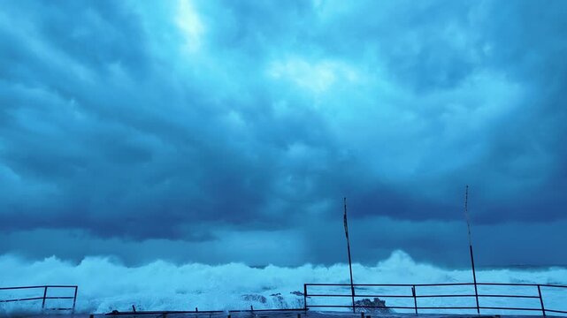 Standing on Flooded Pier &ndash; Enormous Wave Wall Approaching at Eye Level with Dramatic Storm Clouds and Light Break
