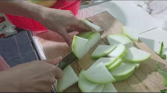 Hand Slicing Fresh Winter Melon on a Wooden Cutting Board