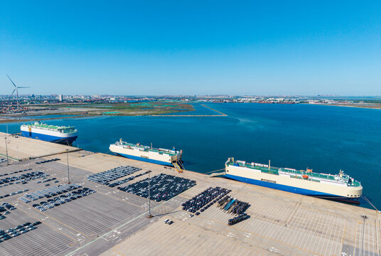 Port terminal with roll-on roll-off ships loading and unloading vehicles under clear sky