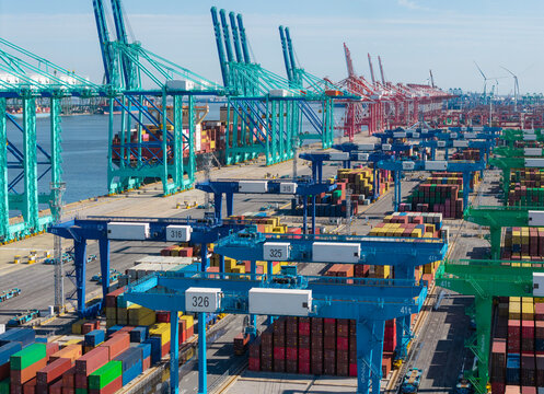 Large port terminal with container handling operations featuring cranes and stacked shipping containers