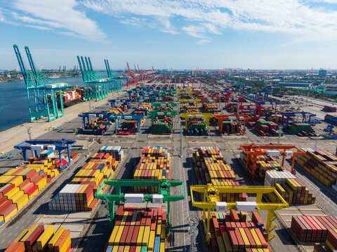 Aerial view of a large port container yard with cranes actively loading and unloading cargo