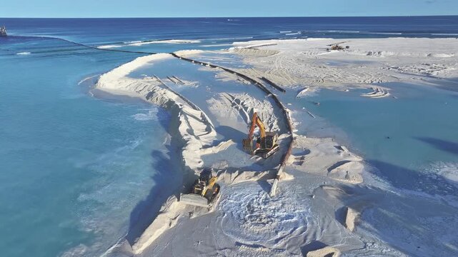Aerial view of heavy machinery and excavators performing land reclamation on the white sands of Gulhi, Kaafu Atoll, Maldives.