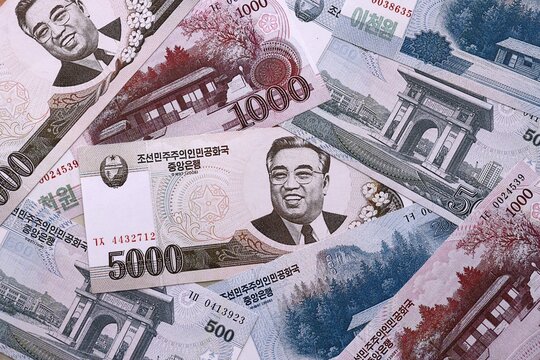North Korean won money bills pile on table. North Korea banknotes of KPW currency close up.