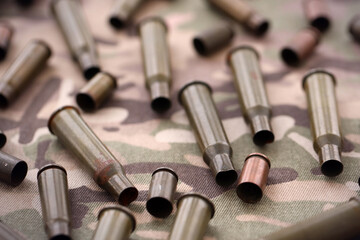 Naklejka premium Big amount of shells cartridges from assault rifle bullets on old camouflage fabric