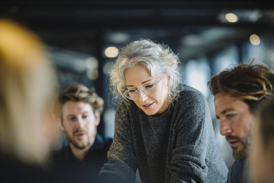 Senior businesswoman leading collaborative team meeting in modern office