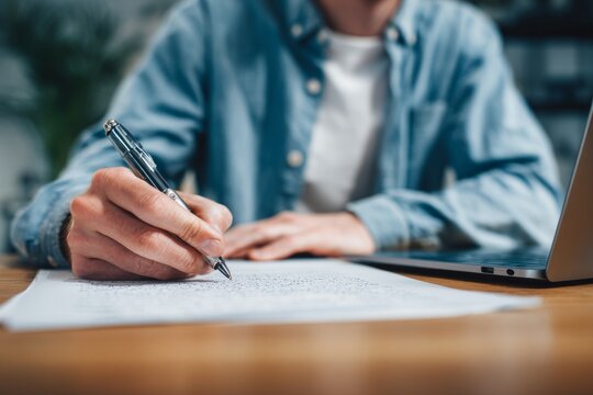 Close-up of person writing notes during remote interview preparation
