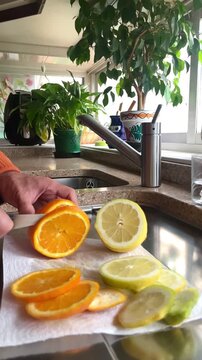 Cortar rodajas naranja y lim&oacute;n de fruta con cuchillo en cocina dom&eacute;stica
