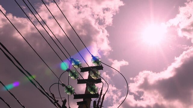 Electric pole, electric grid tower and high-voltage wires, power line close-up, electricity and time lapse of sun sunlight sun rays sunbeams and amazing evening pink blue sky colored clouds.