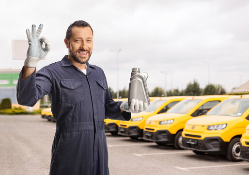 Mechanic holding engine oil in front of vans