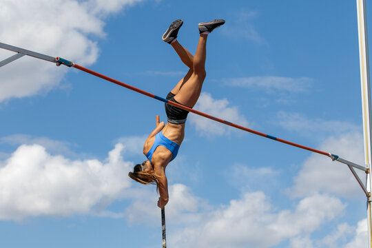 Female athlete upside down with pole in hand in pole vaulting