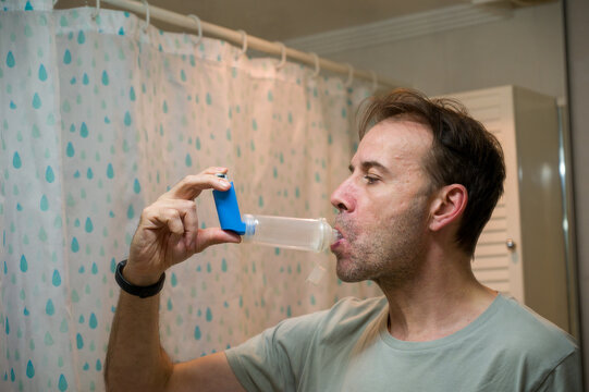 Man using asthma inhaler with spacer for respiratory relief
