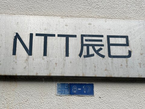 NTT East telecommunications facility signage and blue address plate on a textured exterior wall in the Koto district - Tokyo, Japan, December 20, 2025
