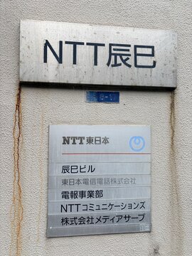 NTT East Tatsumi Building corporate signage and business directory featuring NTT Communications and Media Serve office names on an external wall - Tokyo, Japan, December 20, 2025