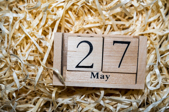 A wooden calendar displaying the date 27 May, surrounded by shredded paper, ideal for themes of time management and planning.