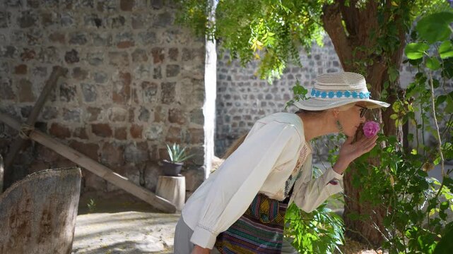 Mature woman enjoys sightseeing at Mission Church in San Ignacio Baja California Mexico while admiring beautiful flowers in spring.