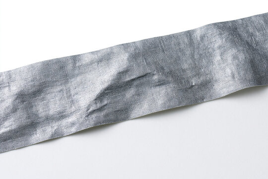 A high-resolution close-up image showing a long strip of silver duct tape with a detailed metallic texture and adhesive wrinkles, positioned diagonally against a plain white background for versatil...