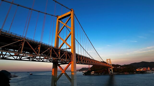 Majestic long view of the Kanmon Bridge illuminated by the setting sun at sunset, Shimonoseki, Japan