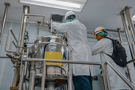 Male work inspection process stainless steel tanks and pipe with pressure meter in equipment tank facility for milk cellar at the with vertical stainless