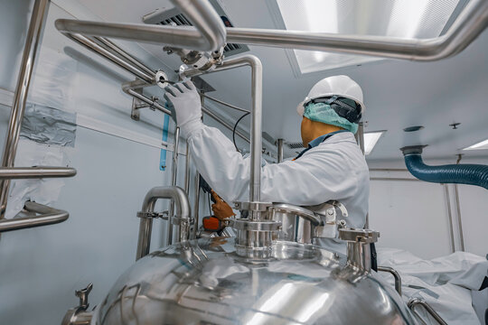 Male work inspection process stainless steel tanks and pipe with pressure meter in equipment tank facility for milk cellar at the with vertical stainless