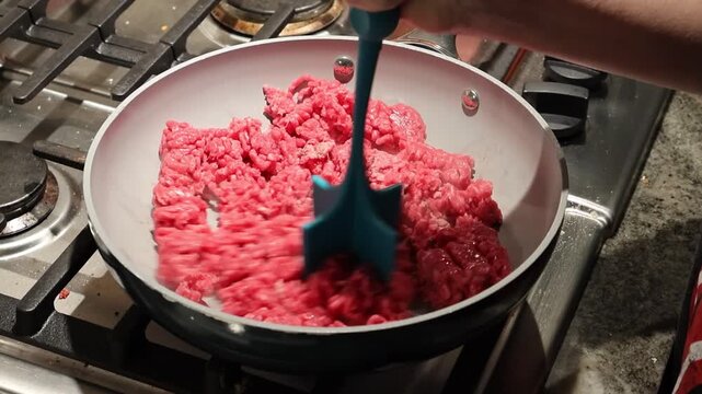 raw ground beef in a pan cooking