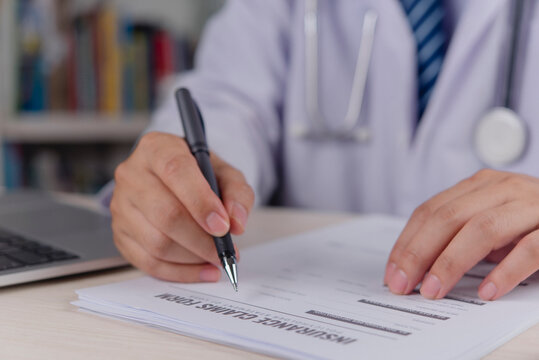 Healthcare provider signing medical chart insurance claim form clipboard pen doctor hand writing diagnostic report clinic workflow patient treatment history office desk professional service.