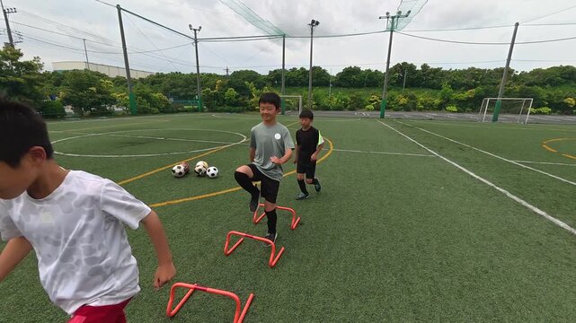 ハードルトレーニングを行うコーチと少年サッカー選手たち