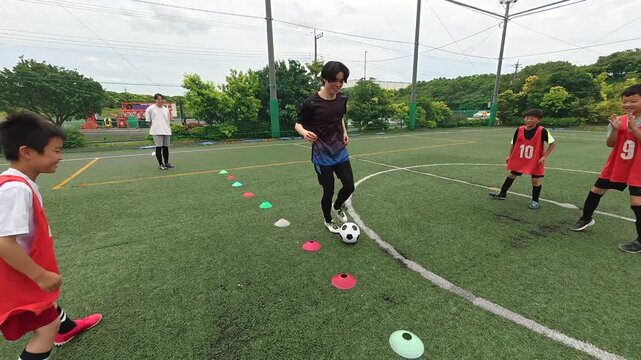 ドリブルを指導する若い男性サッカーコーチ
