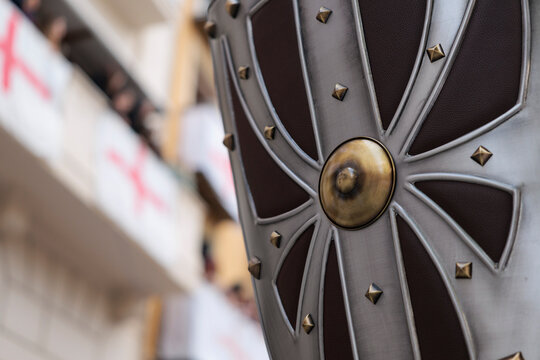 Detalle de escudo medieval con remaches met&aacute;licos y fondo desenfocado en un desfile hist&oacute;rico de moros y cristianos, Alcoy, Espa&ntilde;a