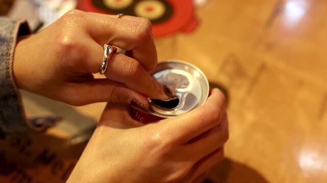 Person opens can of soda with ring pull tab, refreshing drink preparation.