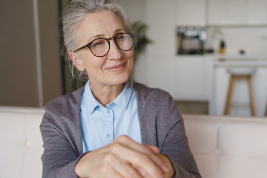 Elderly woman portrait holding wooden walking cane at home in living room, senior lifestyle, independence, healthcare concept, retirement, comfort living and aging with dignity