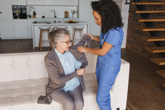 Nurse helping senior woman get dressed at home, elderly care, caregiver assistance, daily living support, healthcare service, independence, comfort and home care concept