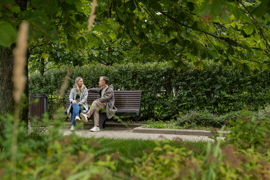 Couple talking on bench in green park