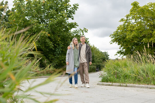 Couple walking and hugging together in green city park